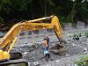 Рабочие-гастарбайтеры бросают камни в ковш экскаватора для его последующей отсыпки в габионы