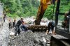 Рабочие-гастарбайтеры бросают камни в ковш экскаватора для его последующей отсыпки в габионы