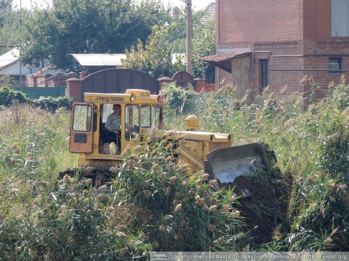 Бульдозер работает в непосредственной близости от частных домов